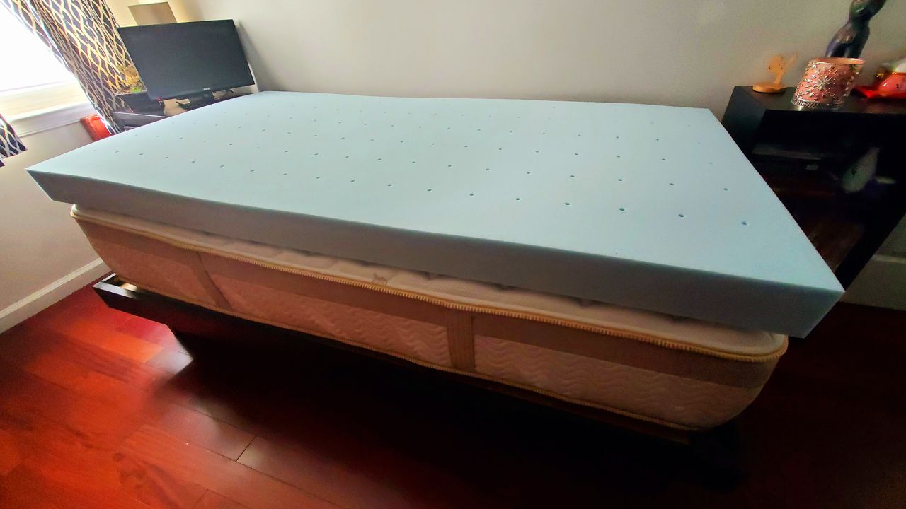 The Lucid 4-inch Gel Memory Foam Mattress Topper on top of a Saatva Loom and Leaf Mattress in a white bedroom.