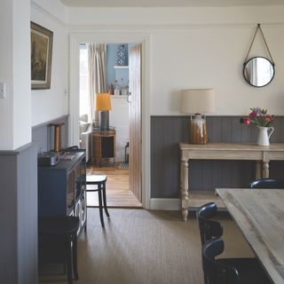 how to panel a wall, dining room with half tongue and groove painted in mid grey, table, sideboard, view to living room, coir carpet, mirror, artwork, lamps