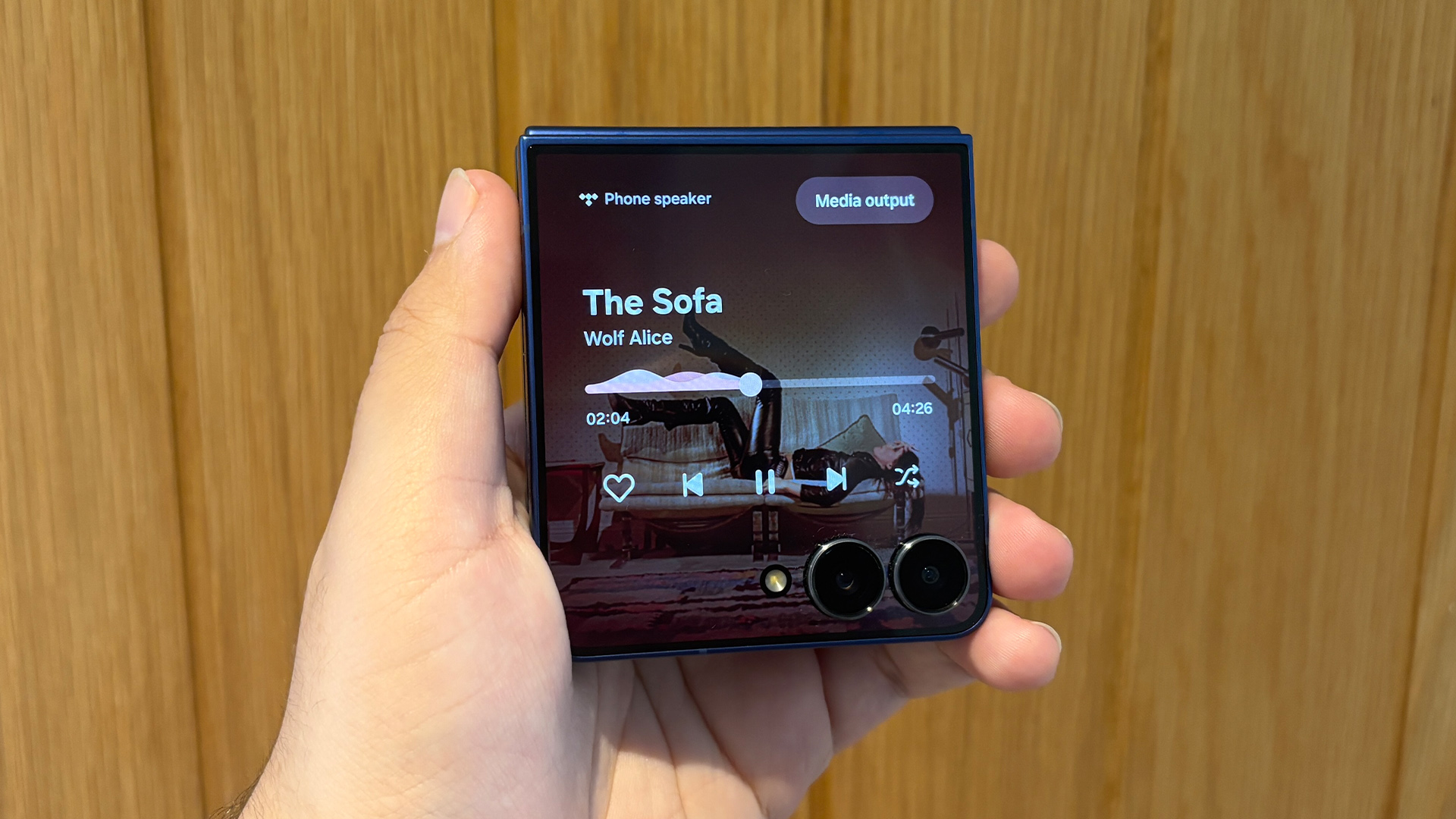 Samsung Galaxy Z Flip 7 smartphone held in hand in folded position showing Wolf Alice tune being played