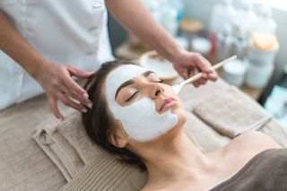 Portrait of a beautiful woman getting a facemask at the spa and taking care of her skin -