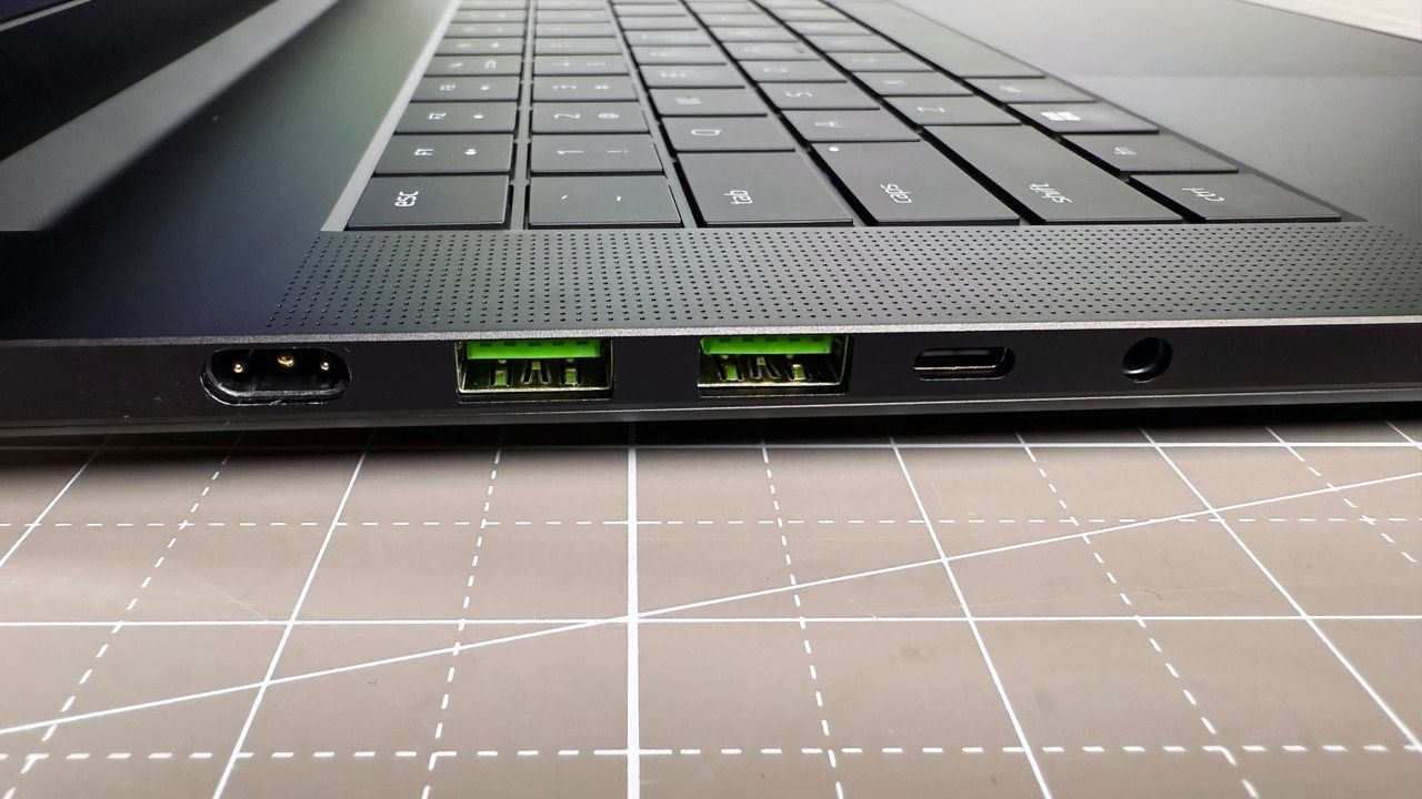 Close up of the left-side port array on the Razer Blade 16 (2025) gaming laptop, on a white and beige desk against a gray backdrop.