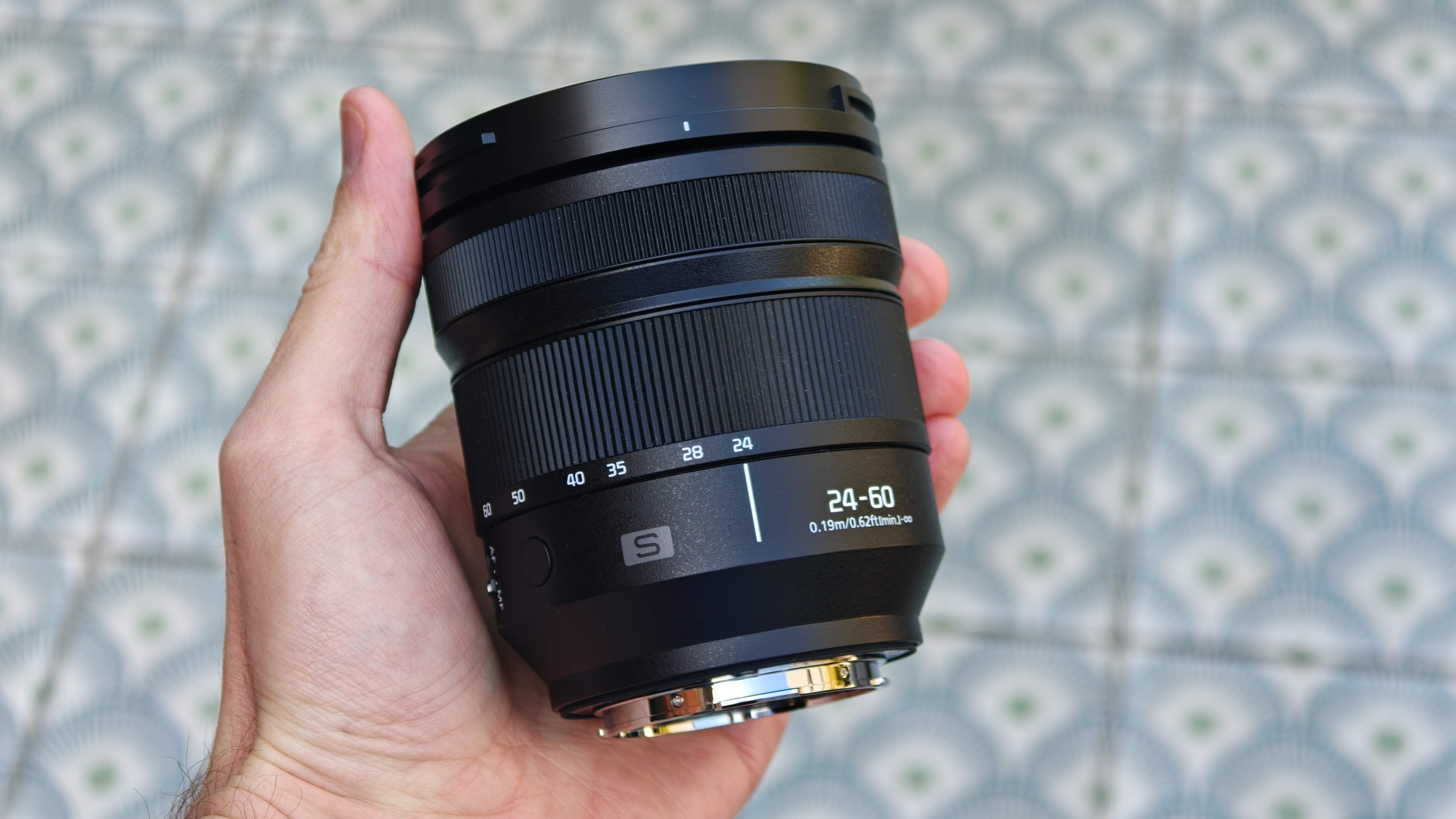 Panasonic Lumix S 24-60mm f/2.8 lens held in a hand
