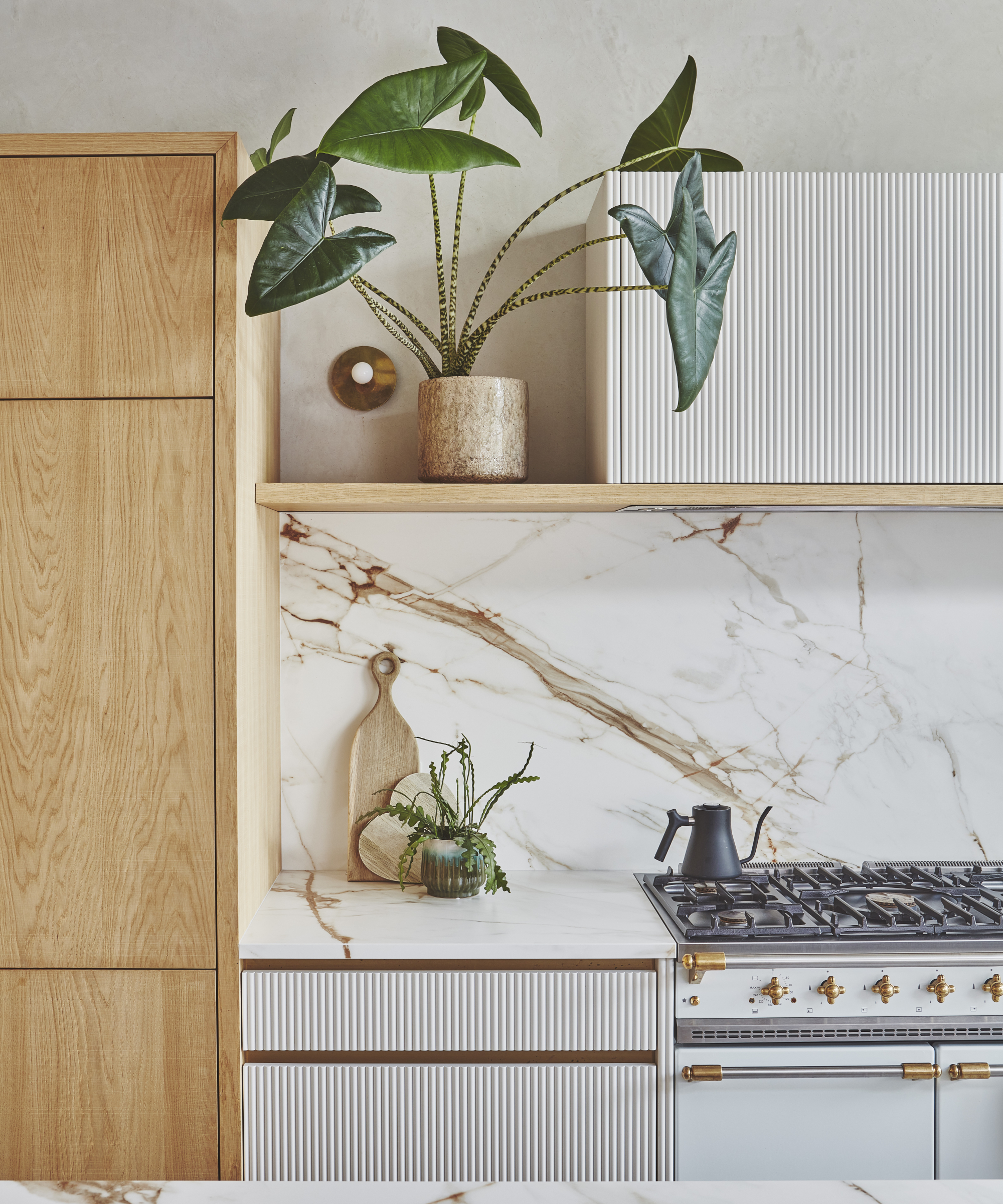 kitchen with brown and white marbled splashbak, wooden units, fluted cabinet doors and white range cooker