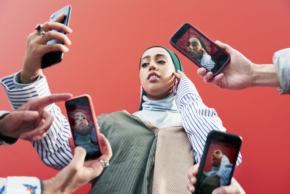 Young woman surrounded by smartphones.