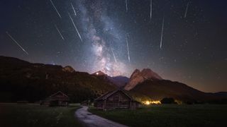 streaks of light cross the starry night sky above a mountain range