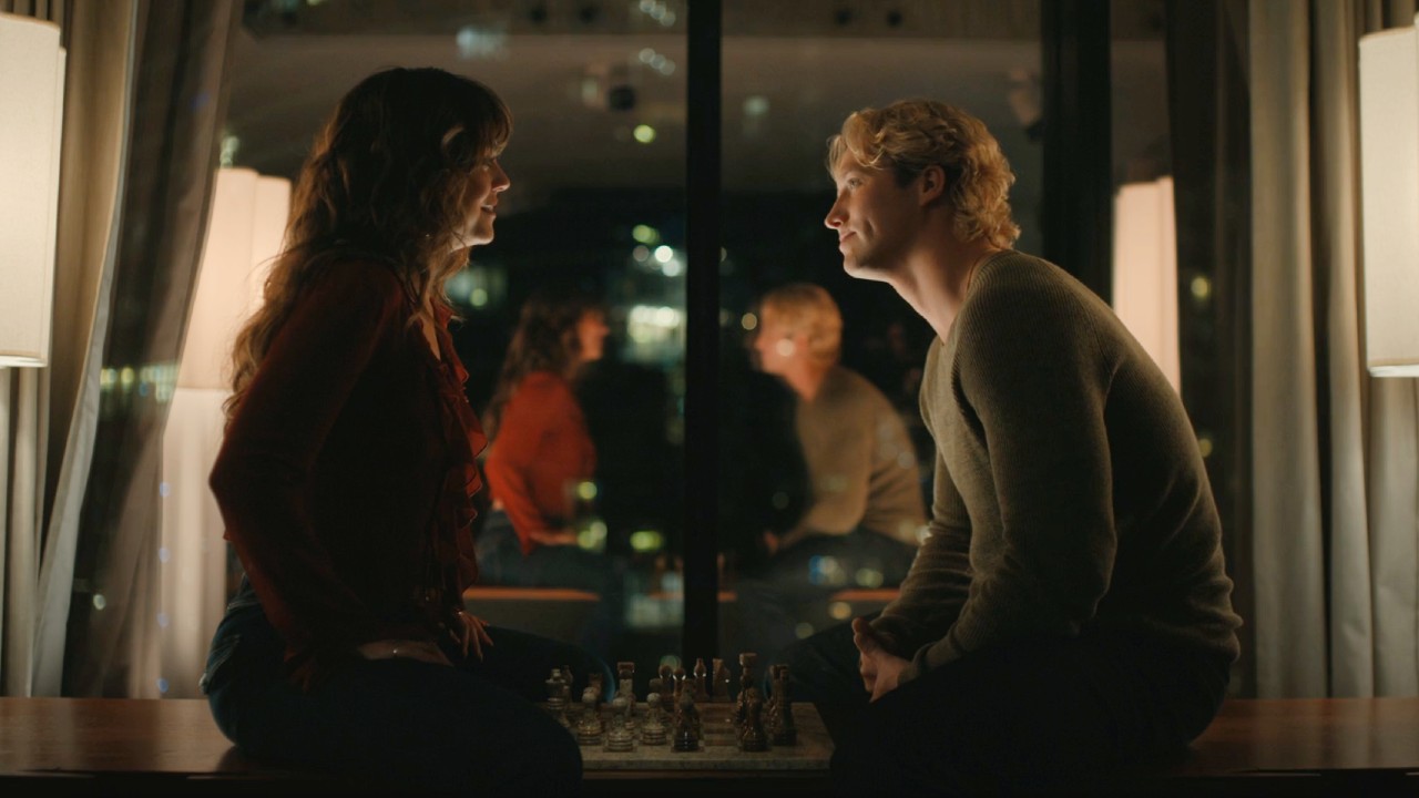 Allie and Dean sitting across from each other playing chess.