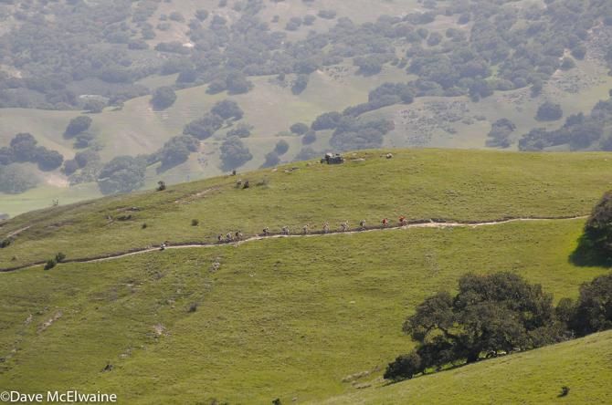 A lead group of eleven men cross a ridge near the end of lap one