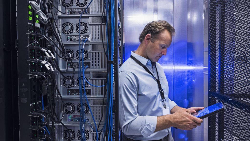 Man using digital tablet in server room - stock photo.