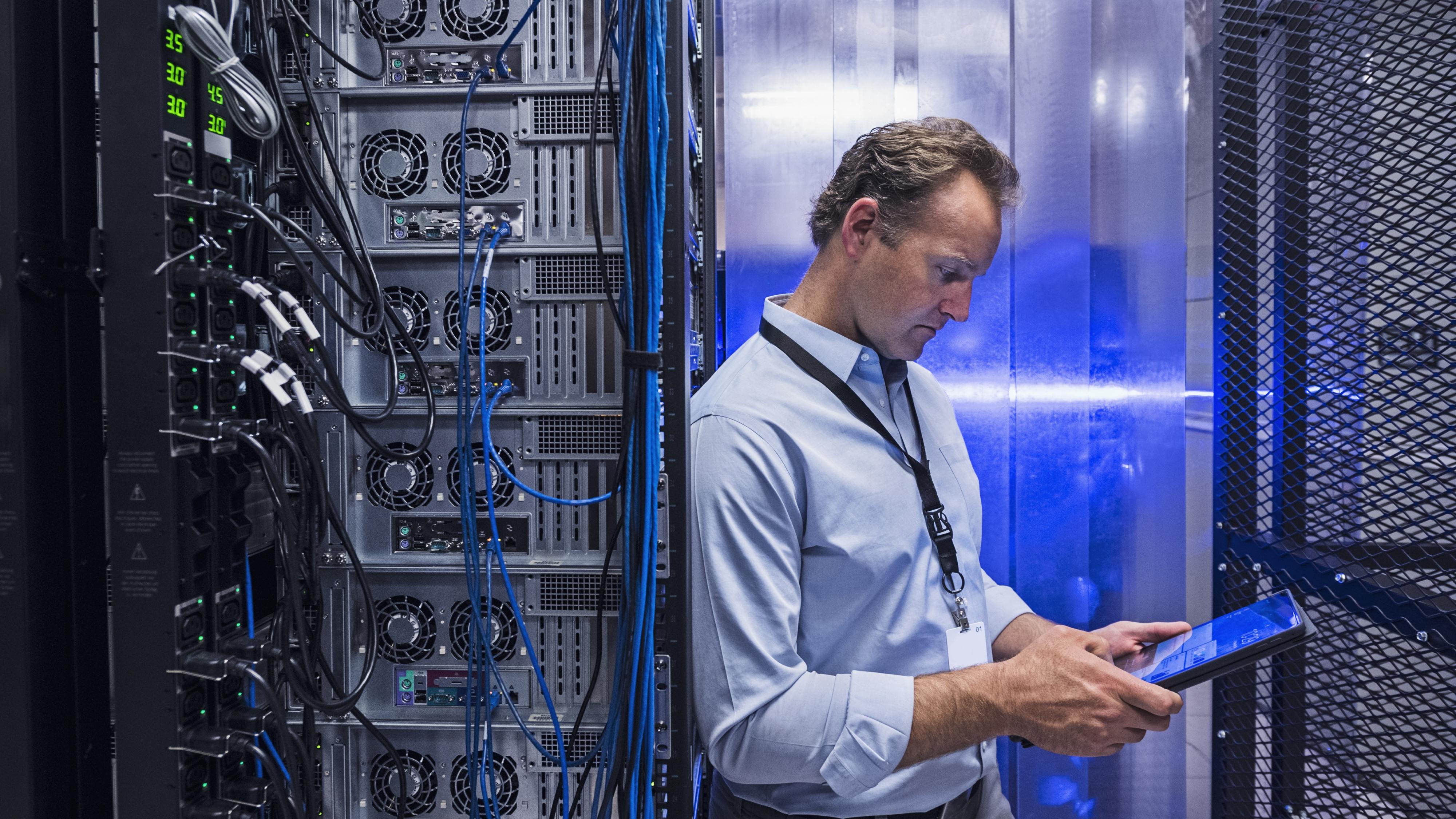 Man using digital tablet in server room - stock photo.