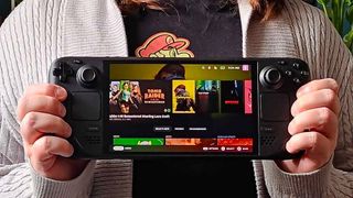 Hands holding Steam Deck OLED with SteamOS main screen displayed.