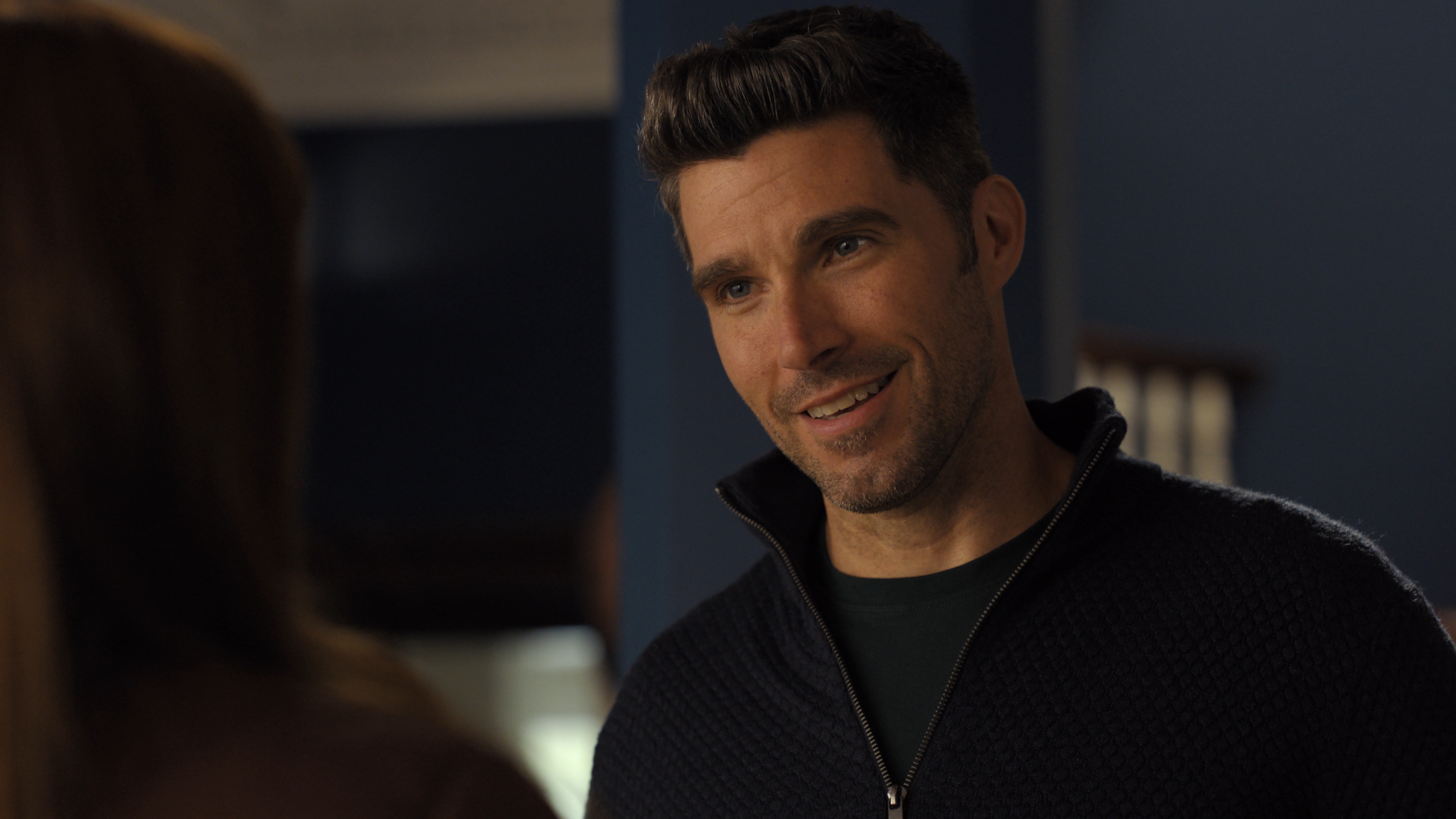 Harmon Walsh as Will Russo wearing a black zip up smiling at a skating rink in Finding Her Edge Season 1