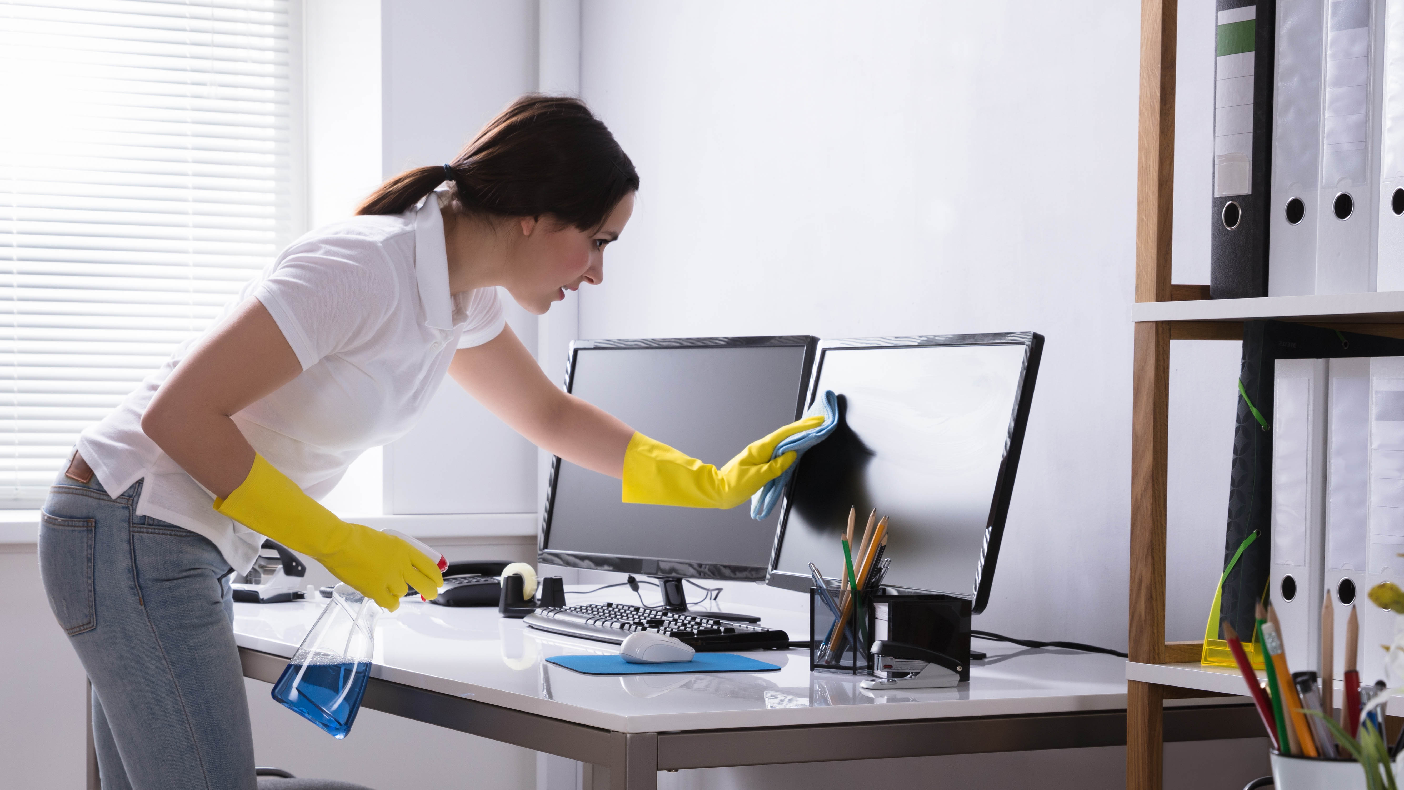 Женщина чистит монитор компьютера