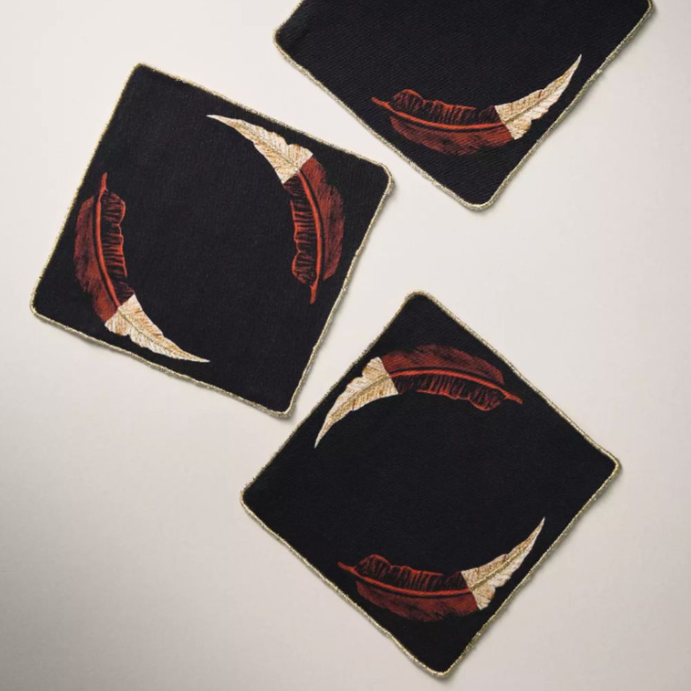 Square black fabric coasters with metallic feather detail