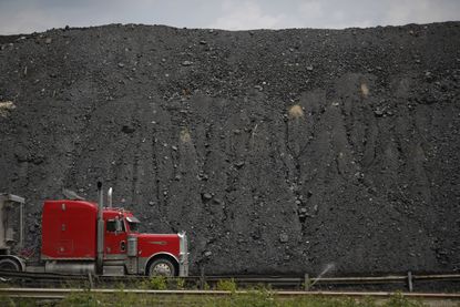 A truck drives past a mound of coal