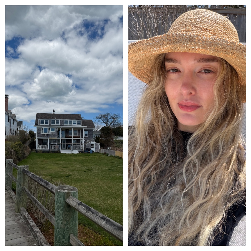a beach house with a grass lawn next to a woman with blonde hair wearing a straw hat