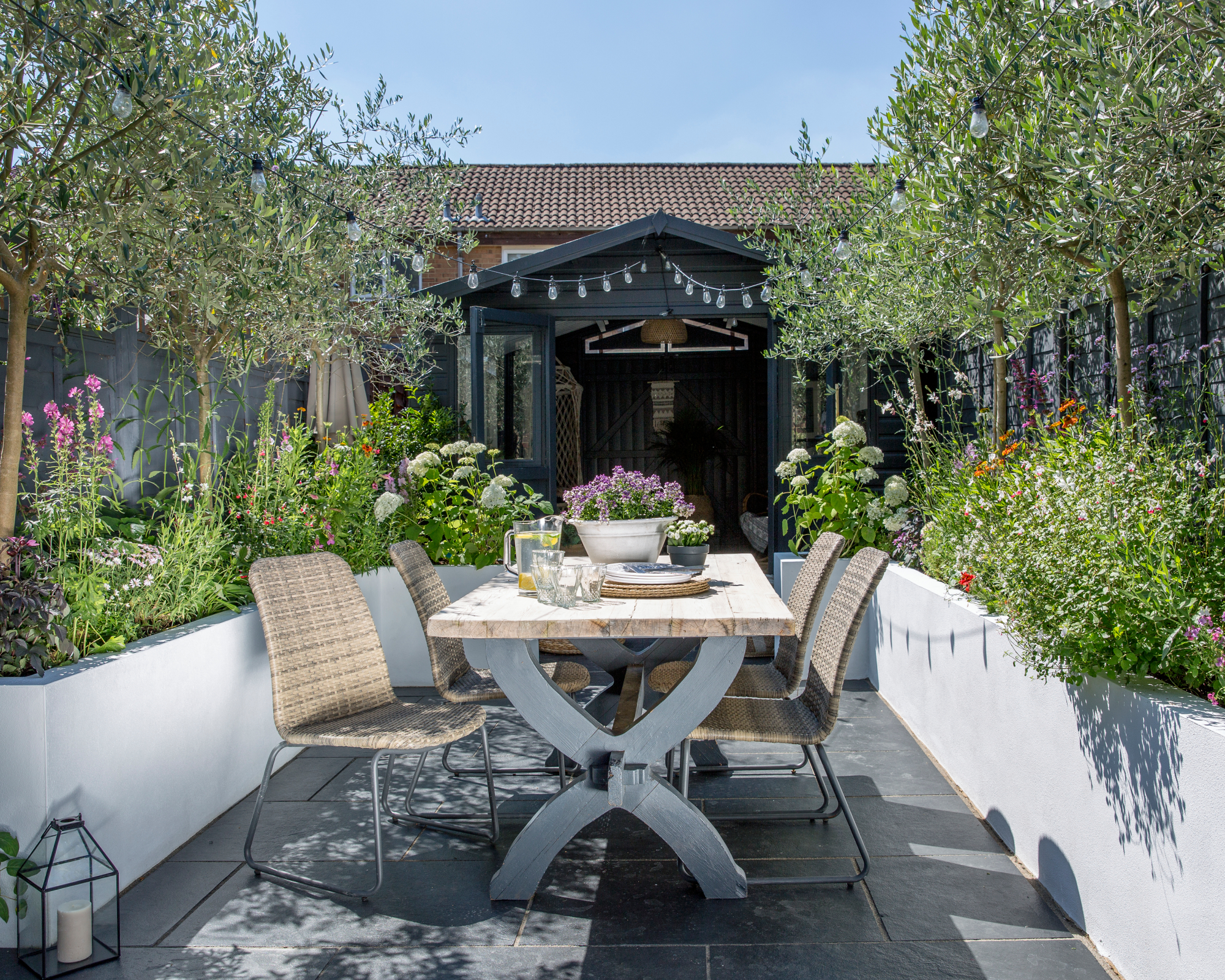 outdoor dining table and chairs in small garden with clever container planting