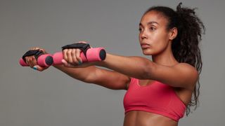 Woman performs front raise shoulder exercise with light hand weights
