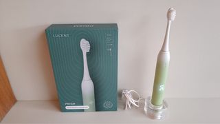 Lucent Prism Sonic electric toothbrush standing on translucent charging platform next to box packaging