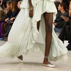 A model wears a green gown and white lace-up shoes on the Chloé runway