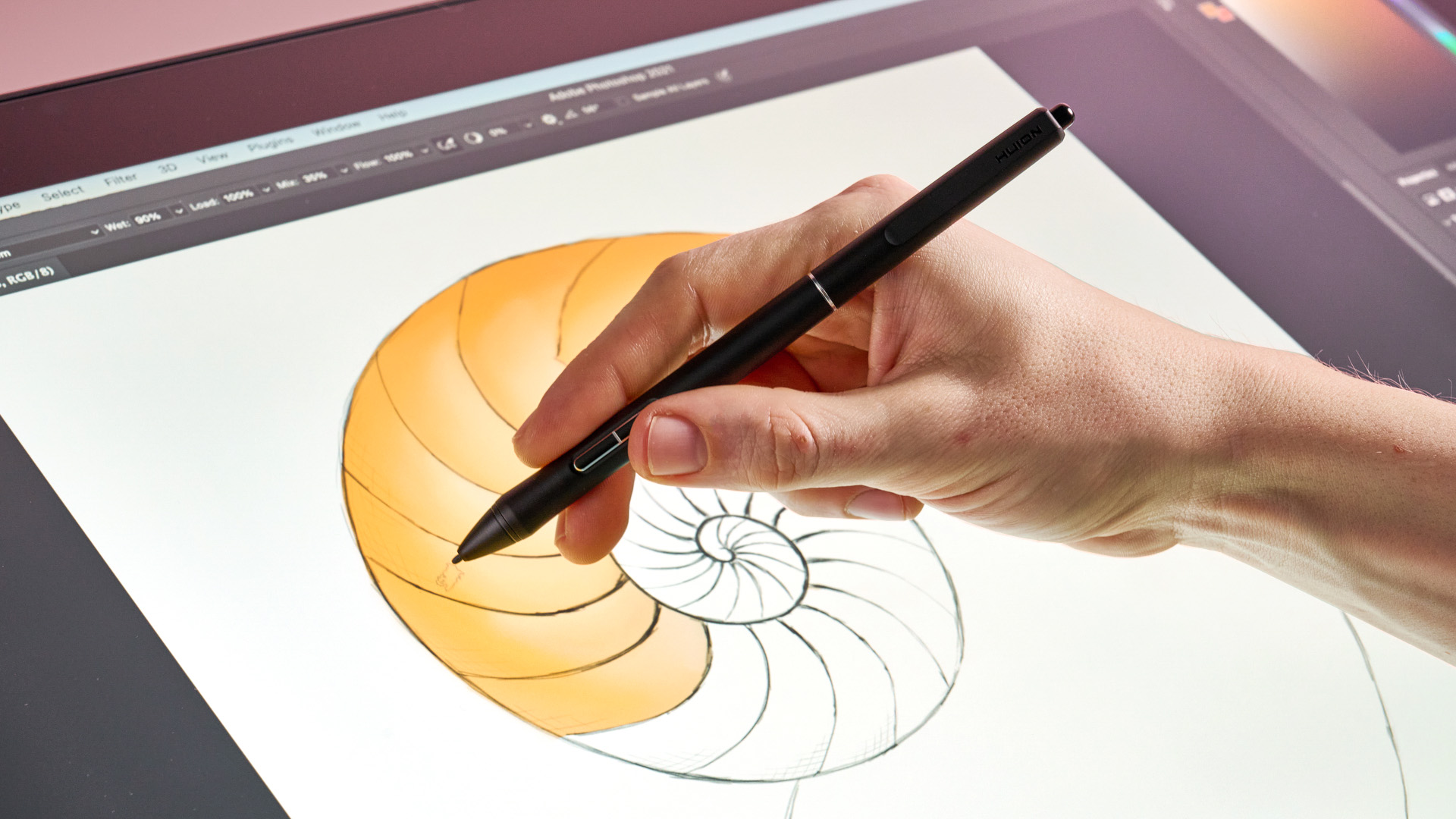 A hand paints with an orange oil brush on a sketch of a nautilus shell on the Huion Kamvas Pro 24 Gen 3.