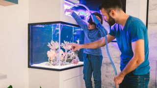 child and father cleaning a fish tank with a vacuum