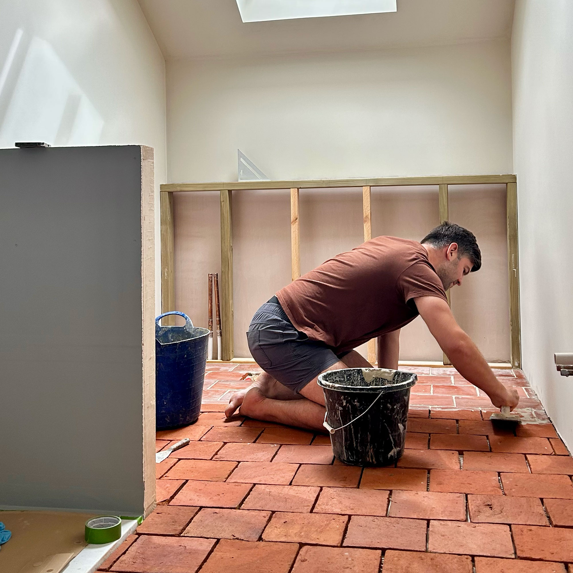 Man on all floors treating terracotta tiled floor in room mid renovation