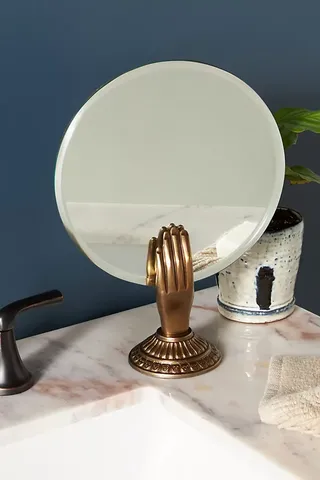 A tabletop round mirror with a hand stand