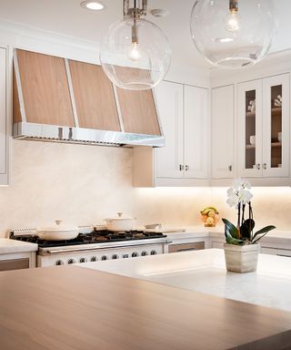 A white kitchen with wooden accents on the island and range hood