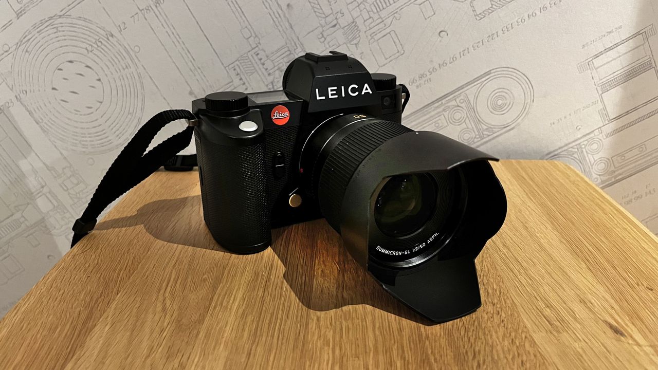 The Leica SL3 shot on a wooden platform with a Leica wallpaper behind