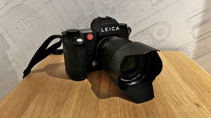The Leica SL3 shot on a wooden platform with a Leica wallpaper behind
