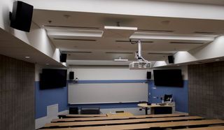 An empty classroom with several Sennheiser TeamConnet Ceiling 2 devices ready for hybrid learning.
