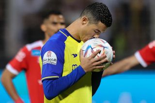Cristiano Ronaldo kisses the ball before taking a penalty for Al-Nassr against Al-Wehda in the Saudi Pro League in February 2023.
