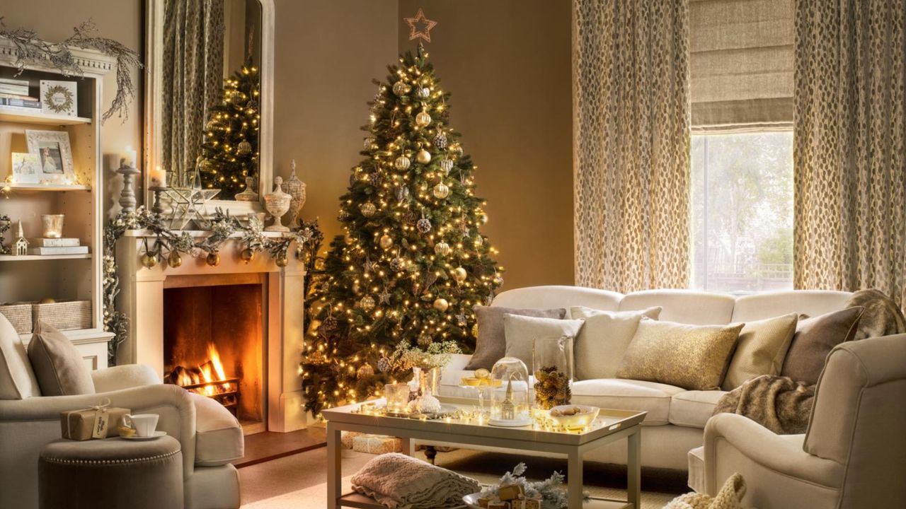 Decorated Christmas tree in a country style brown living room, white sofa, cushions, fireplace, lit fire, decorated mantelpiece, large mirror, coffee table. Pub Orig