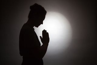 silhouette of praying woman