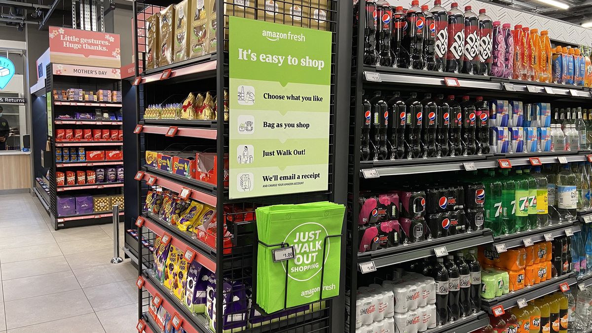 A container of Amazon Fresh bags for life at the end of an aisle below a sign saying &amp;quot;Choose what you like, bag as you shop, just walk out! We&amp;#039;ll email you a receipt&amp;quot;