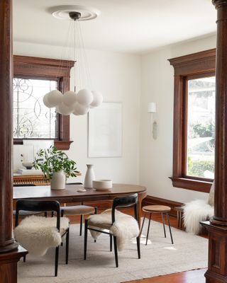 minimalist dining room with oval wood dining table and chairs covered in sheepskin throws