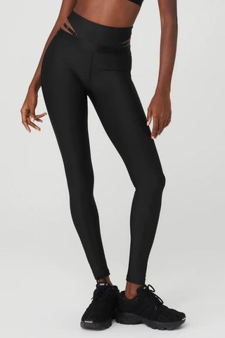 woman wearing black high waisted leggings with cut-out side detail from the alo yoga sale