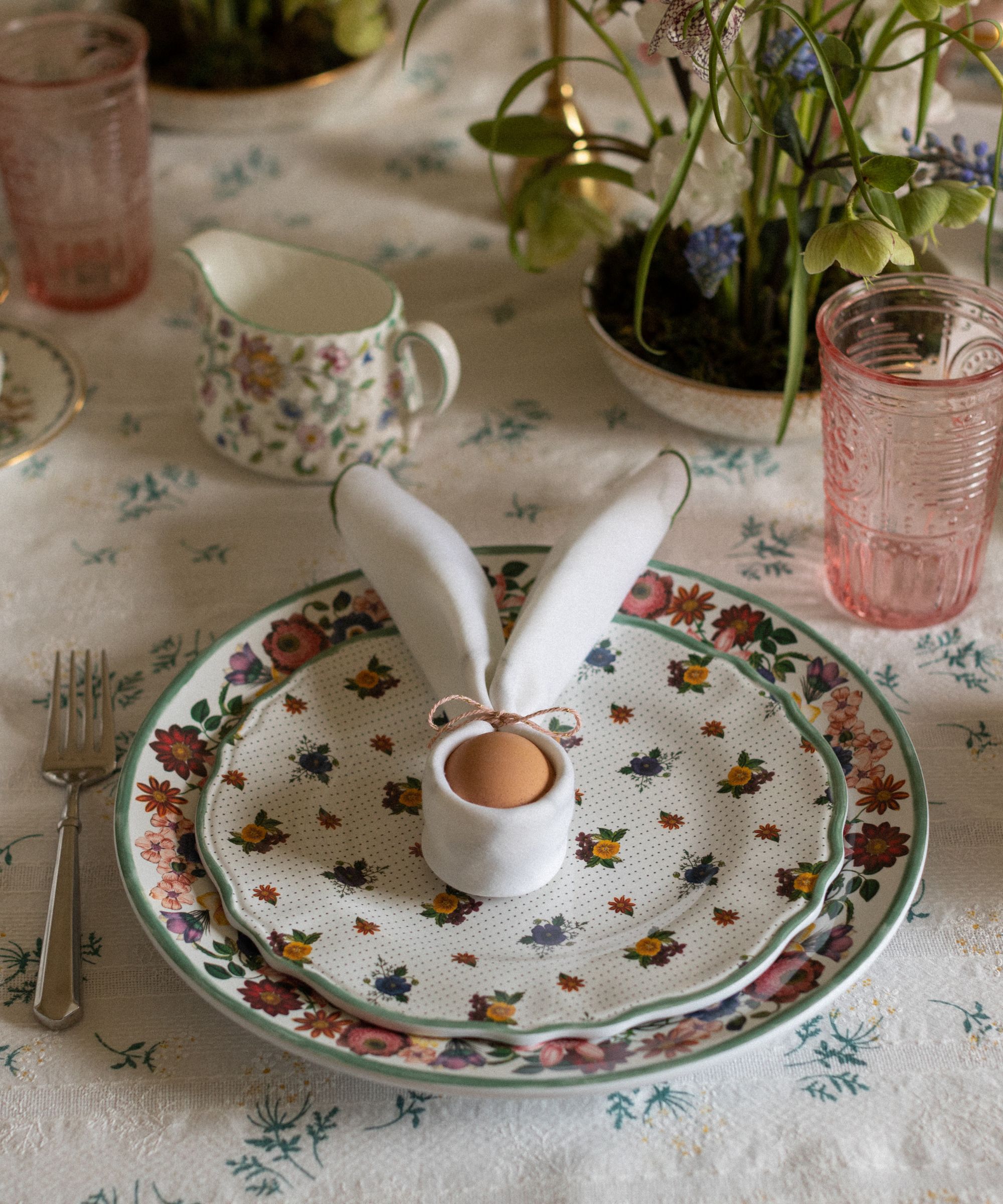 napkin folded around an egg to resemble the easter bunny on a vintage plate for easter table