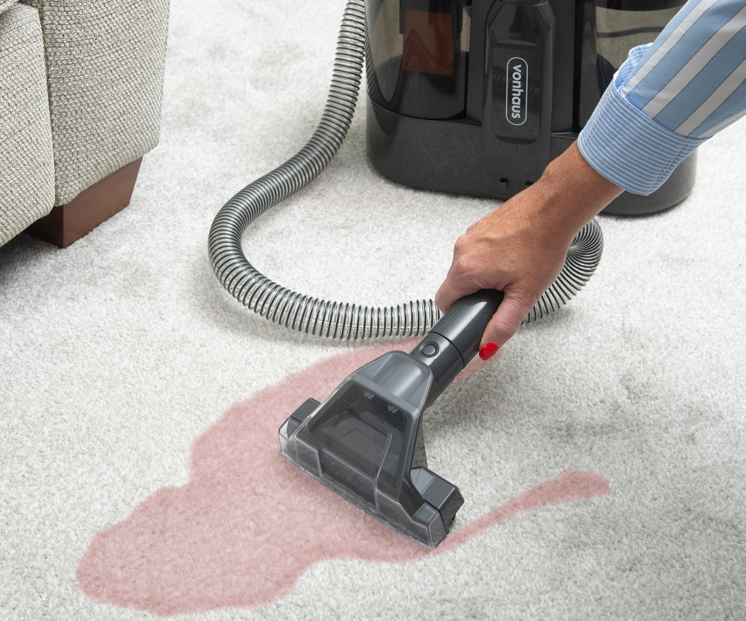 woman using spot cleaner to clean white carpet