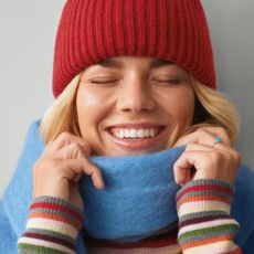 blonde woman smiling wearing scarf and red beaning