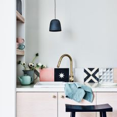 Kitchen with patchwork style tiled splashback behind sink and under pendant light
