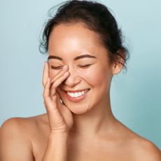 a model smiling with her eyes closed - best eye creams for wrinkles