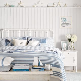 bedroom with white panel wall white bed with blue and white cushion