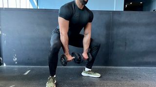 a photo of trainer Ali Malik performing a Dumbell Sumo Squat