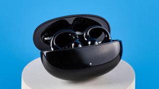 the edifier lolliclip earbuds in black photographed against a blue background, with a cuff style and black charging case