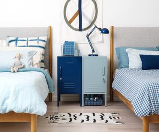 bedroom with two single wooden beds and one dark blue and one light blue bedside locker