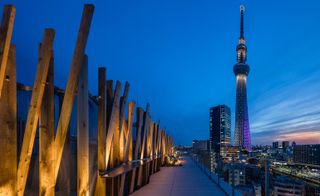 Seen at dusk, wooden batons of One@Tokyo hotel exterior and in background Tokyo Skytree tower