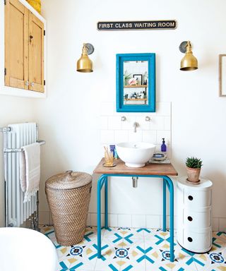 Light bathroom with patterned floor tiles and wicker laundry basket next to basin on old school table