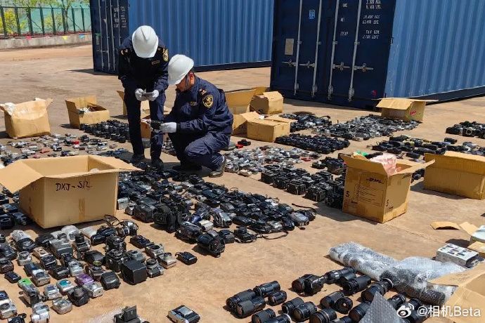 Two customs officers inspect opened boxes of used camera equipment, seized at the Chinese border