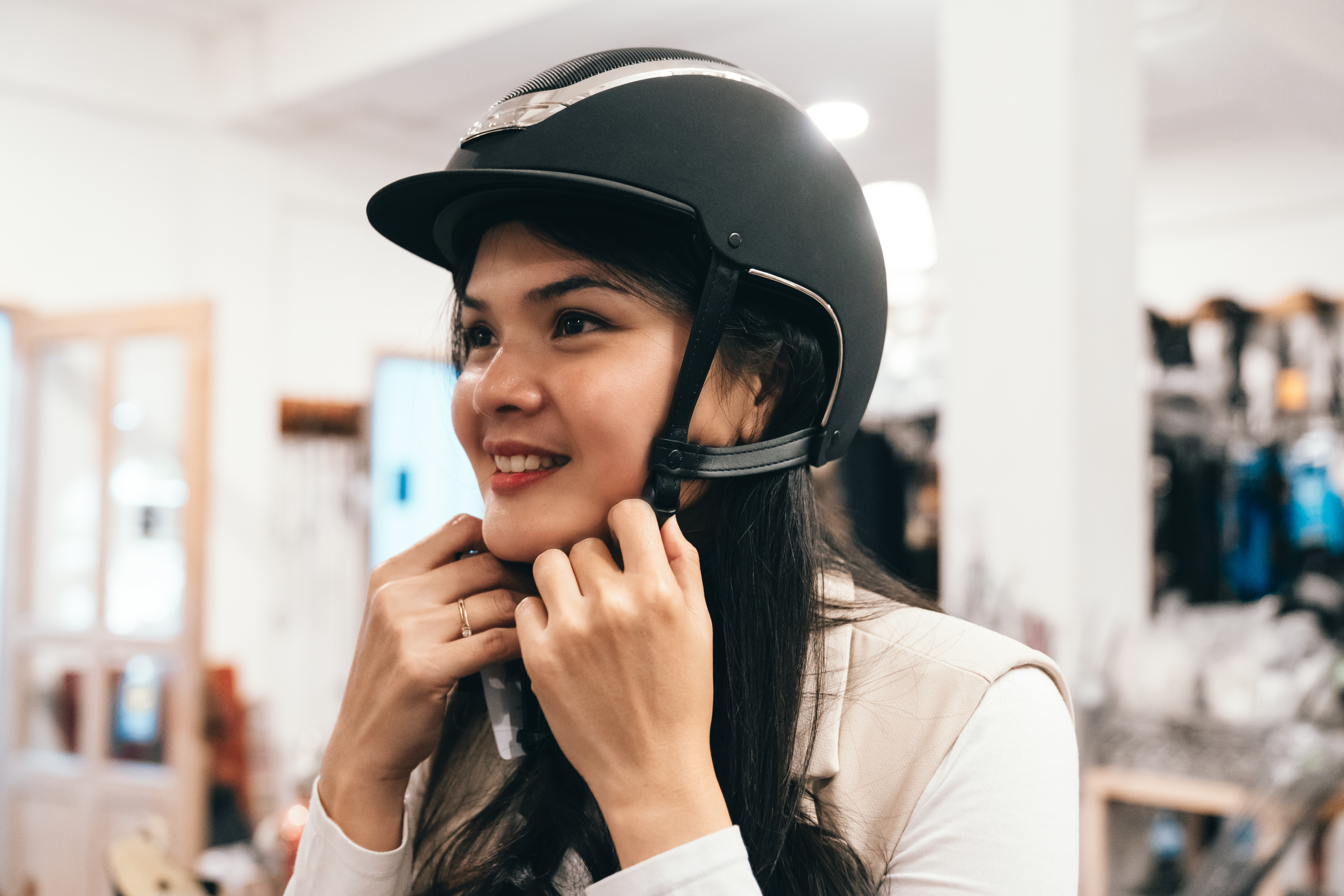 Lady trying on a riding hat and adjusting chin strap